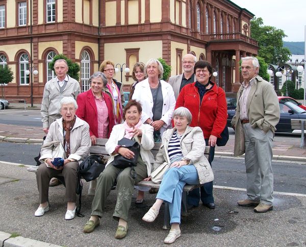 Die Teilnehmerschar wartet am Neustadter  Bahnhof vor dem Saalbau (im Hintergrund) auf den Bus zum Hambacher  Schloss.